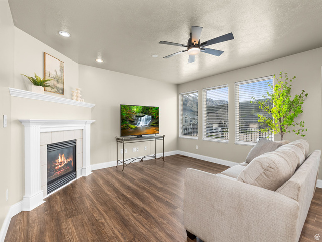 6849 North Black Powder Road Mountain Green, UT 84050 - Photo 3 of 43 Living area featuring wood-finish flooring and a corner fireplace with a white mantel and tiled surround