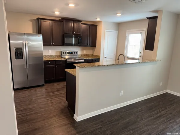 a kitchen with stainless steel appliances granite countertop a refrigerator a sink a stove a microwave and wooden floor