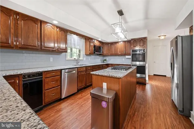 a dining room with wooden floor a chandelier a wooden table and chairs