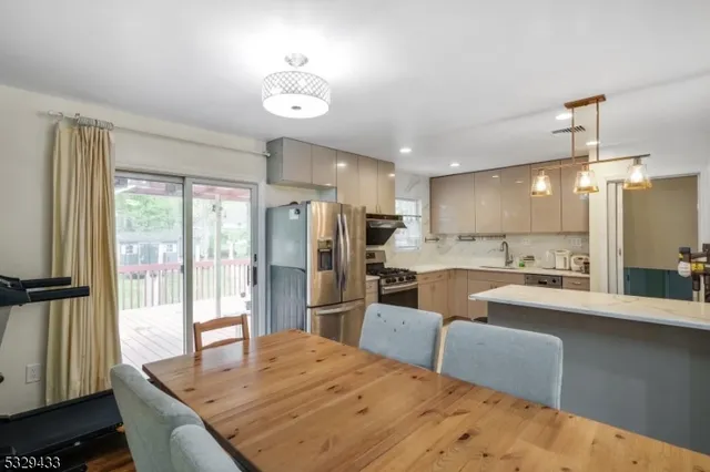 a kitchen with stainless steel appliances kitchen island granite countertop a refrigerator a sink dishwasher with a dining table and chairs with wooden floor