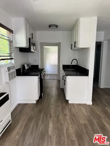 a kitchen with stainless steel appliances a stove a sink a microwave a refrigerator and cabinets