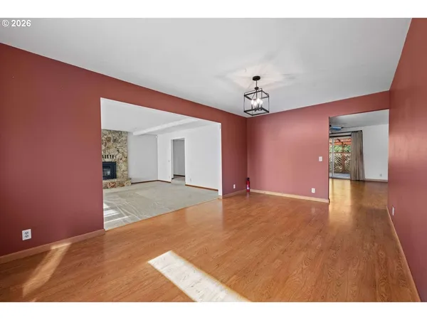 a view of an empty room with window and wooden floor