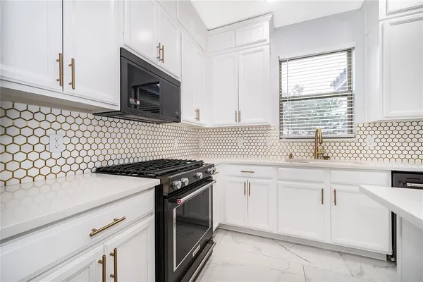 a kitchen with granite countertop cabinets stainless steel appliances a sink and a window