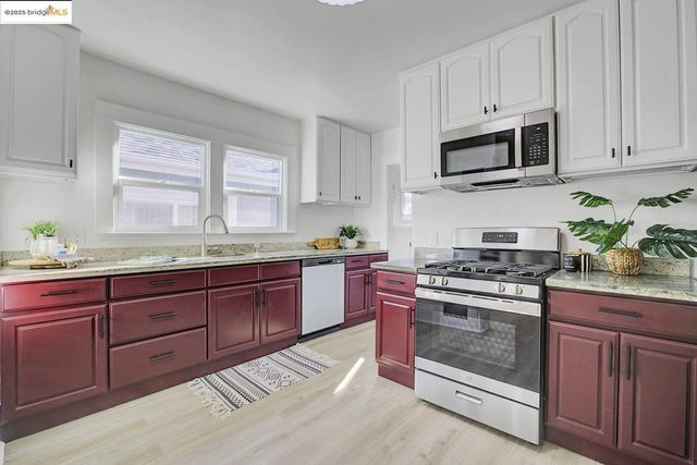 a kitchen with stainless steel appliances granite countertop white cabinets a sink and dishwasher a stove top oven with wooden floor