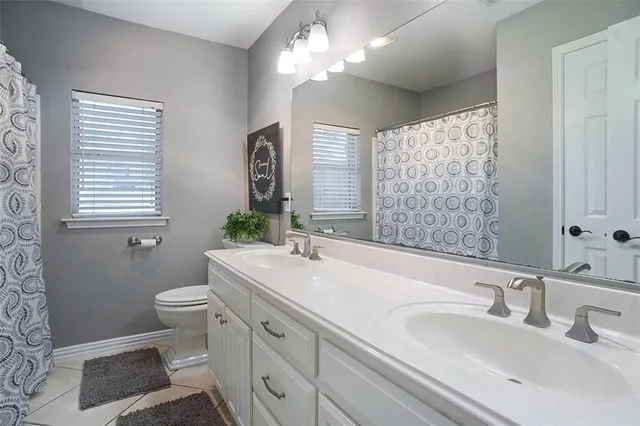 a bathroom with double vanity sink a toilet and a mirror