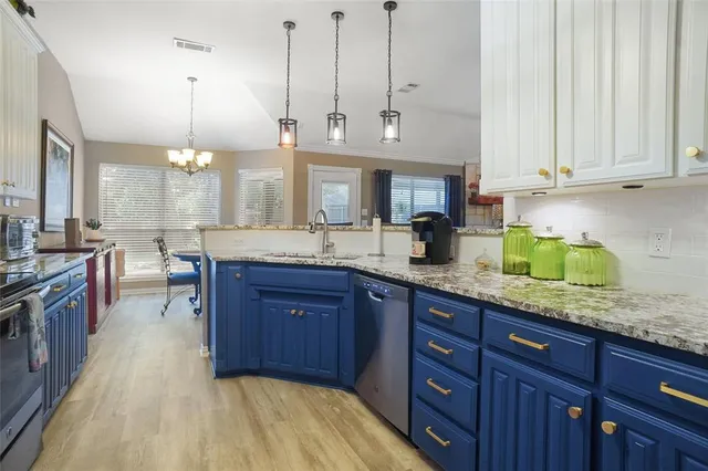 a kitchen with stainless steel appliances granite countertop a stove a sink and a white cabinets
