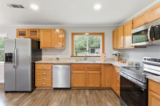 a kitchen with stainless steel appliances granite countertop a sink a stove a refrigerator cabinets and a window