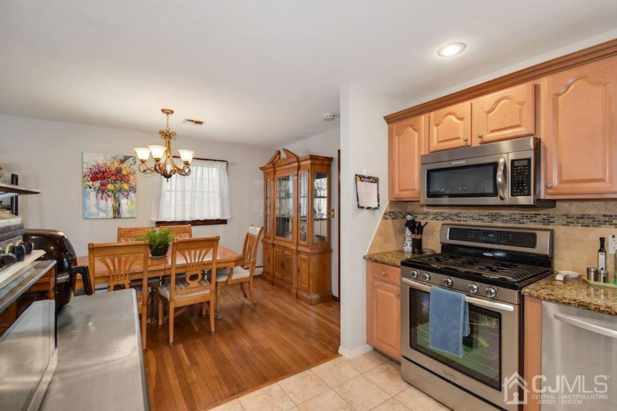 4 Finley Road Edison, NJ 08817 - Photo 11 of 32 a kitchen with stainless steel appliances a stove a kitchen island hardwood floor and a sink