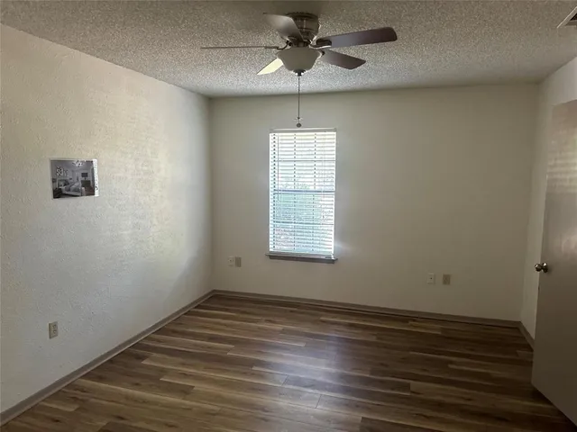 an empty room with wooden floor chandelier fan and windows