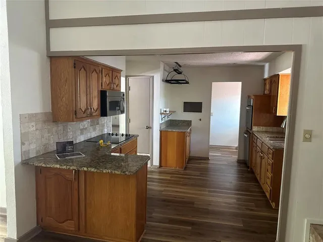 a kitchen with granite countertop a refrigerator stove and oven