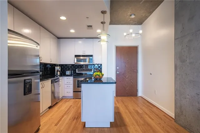 a kitchen view with stainless steel appliances a refrigerator and a wooden floor
