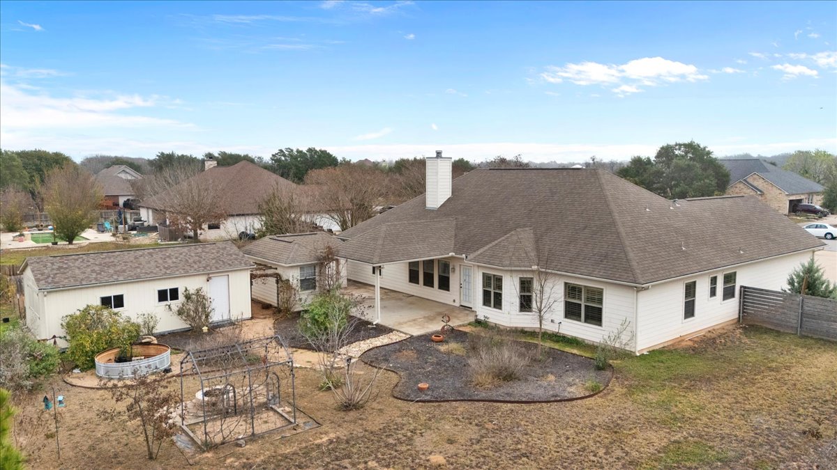 106 Spring Meadow Road Bastrop, TX 78602 - Photo 33 of 39 Back of house with a patio, a fenced backyard, a chimney, an outbuilding, and a shingled roof