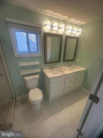 a bathroom with a granite countertop toilet sink and mirror