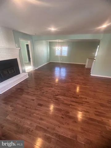 a view of empty room with wooden floor and fireplace