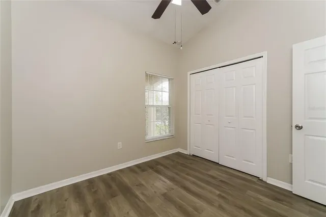 an empty room with ceiling fan and window