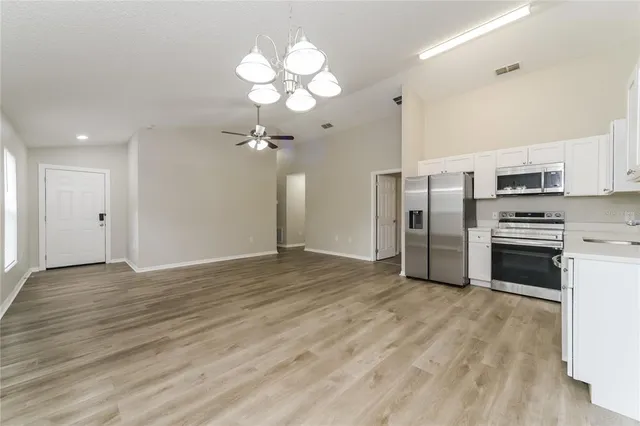 a view of a kitchen with stainless steel appliances a refrigerator and a stove top oven