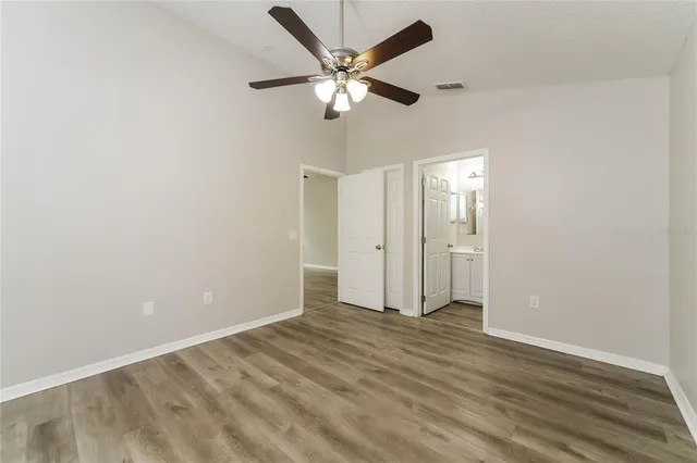 an empty room with wooden floor and ceiling fan