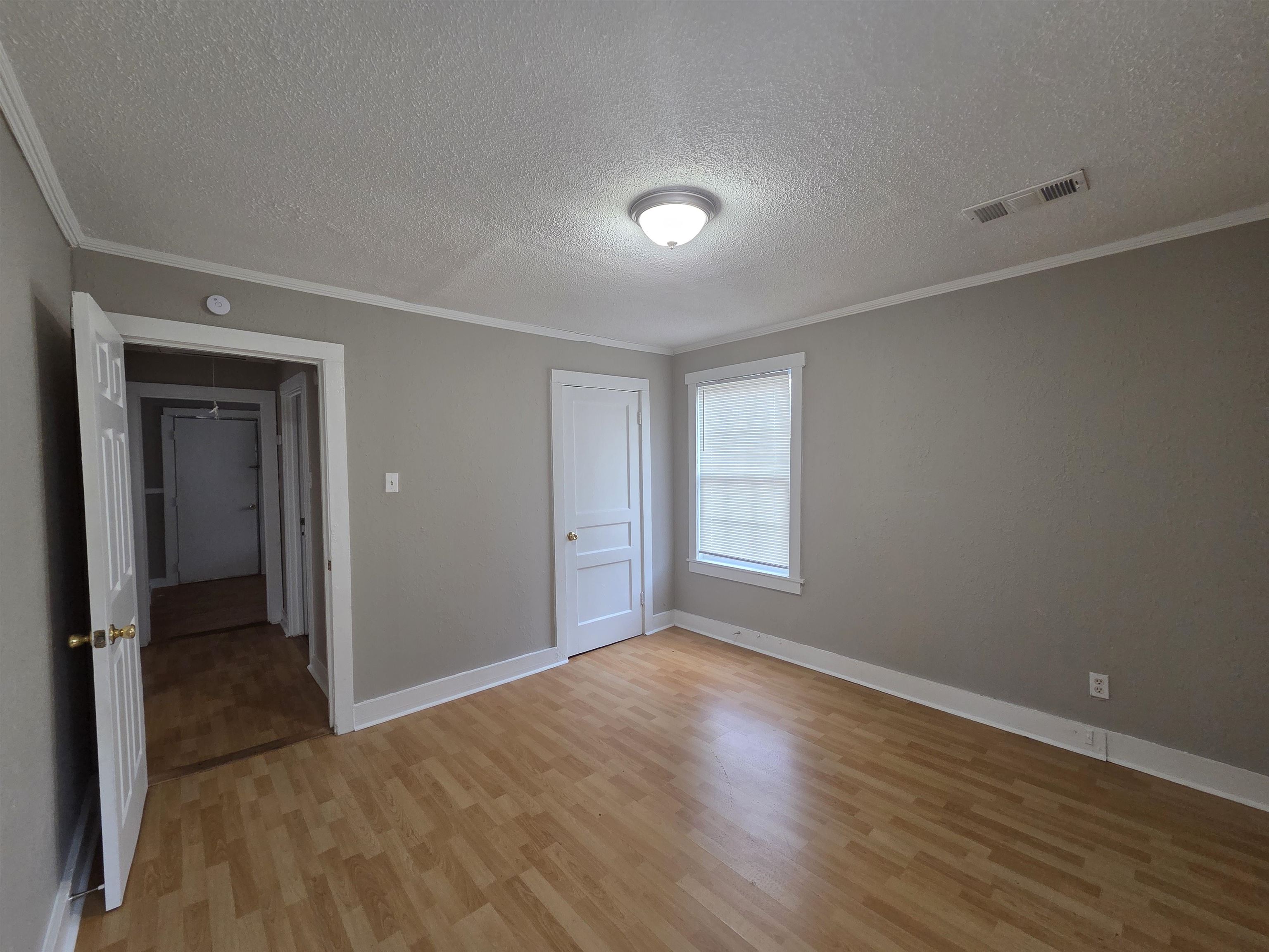 3458 Radford Road Memphis, TN 38111 - Photo 9 of 18 Unfurnished bedroom featuring light wood-style flooring, a textured ceiling, crown molding, and a closet