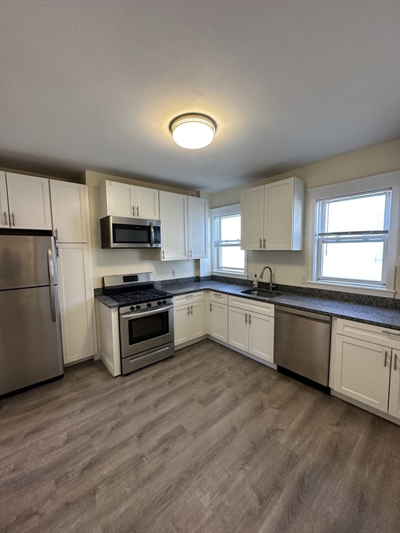 a large kitchen with cabinets wooden floor and stainless steel appliances