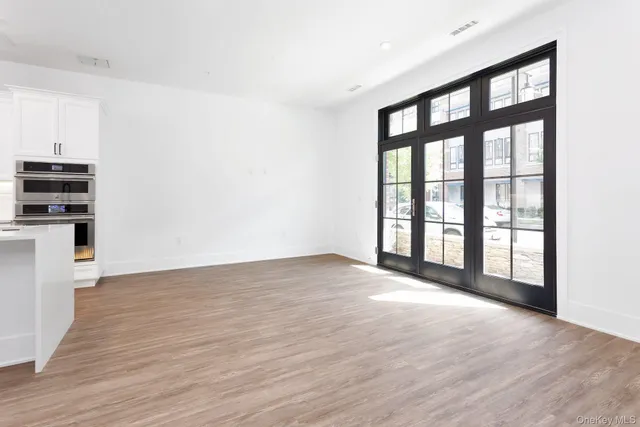 a view of an empty room with a window and wooden floor