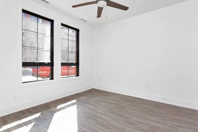 an empty room with wooden floor and windows
