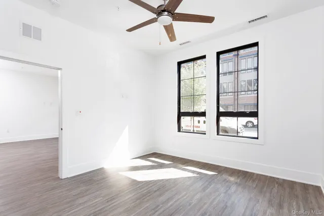 a view of an empty room with wooden floor and a window