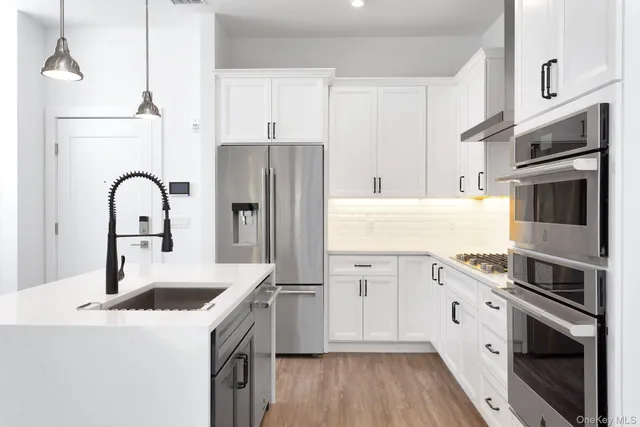 a kitchen with stainless steel appliances granite countertop a white stove top oven a sink and dishwasher with wooden floor