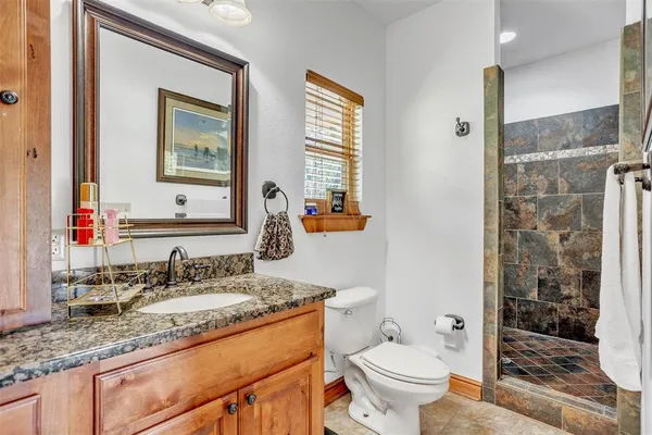a bathroom with a granite countertop sink toilet and shower