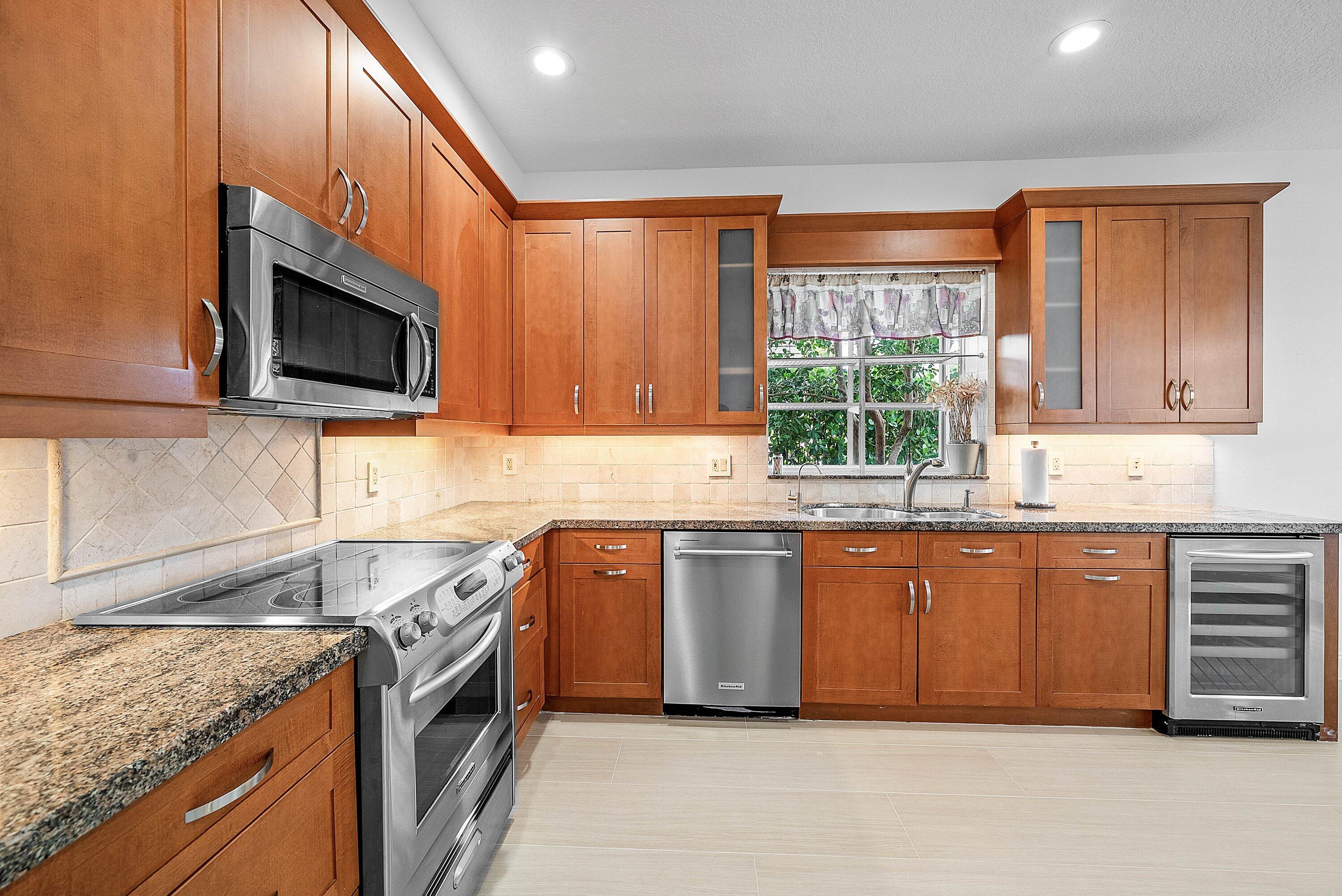 5855 Northwest 42nd Way Boca Raton, FL 33496 - Photo 13 of 77 a kitchen with stainless steel appliances granite countertop wooden cabinets a stove top oven a sink and dishwasher