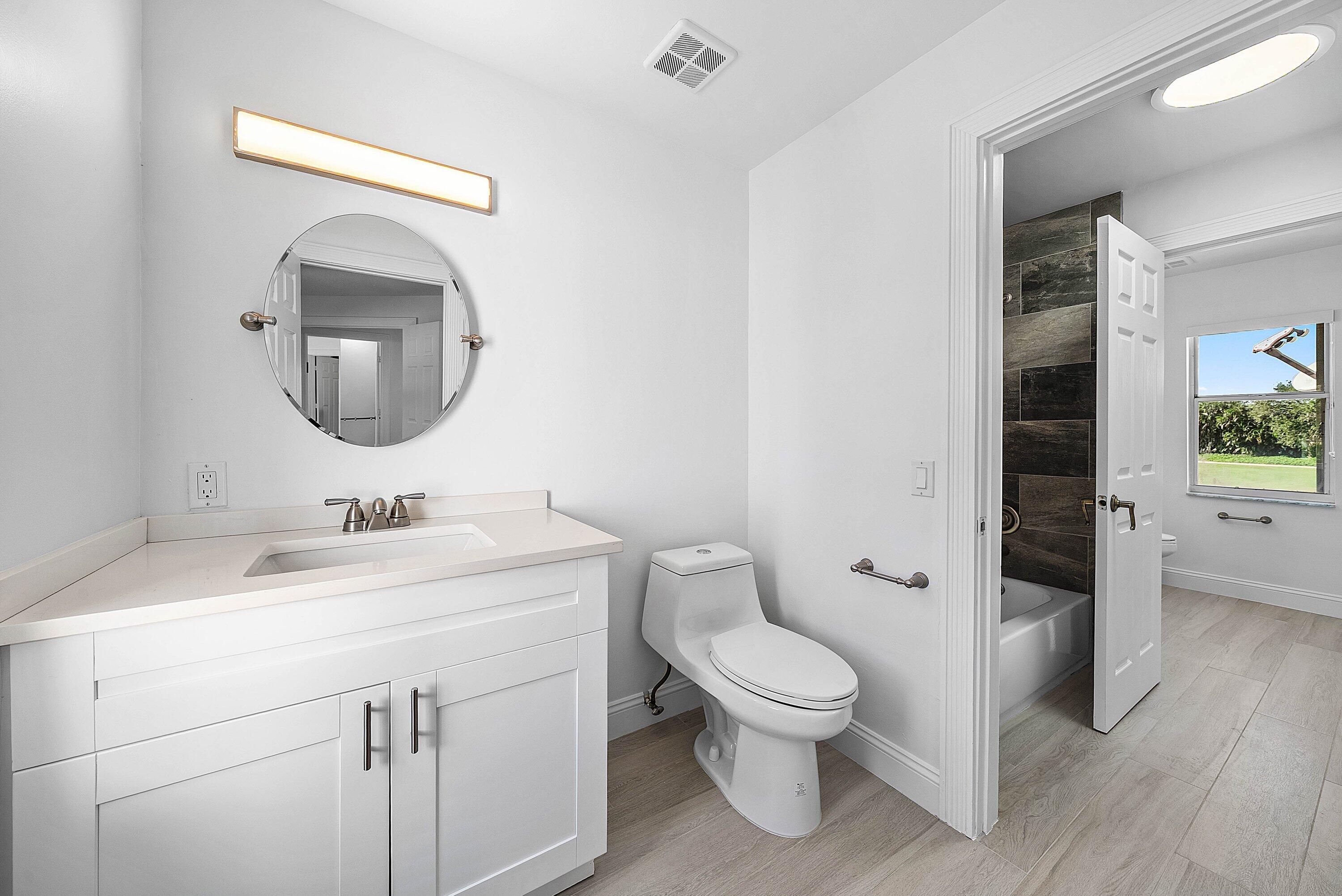 5855 Northwest 42nd Way Boca Raton, FL 33496 - Photo 32 of 77 a bathroom with a toilet a sink and mirror