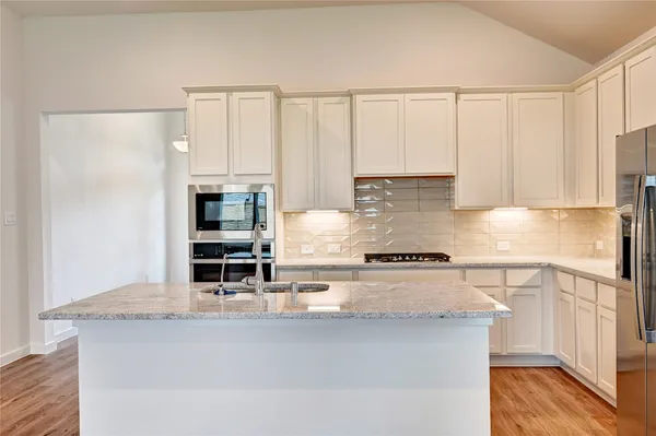 a kitchen with stainless steel appliances granite countertop a stove a sink and white cabinets