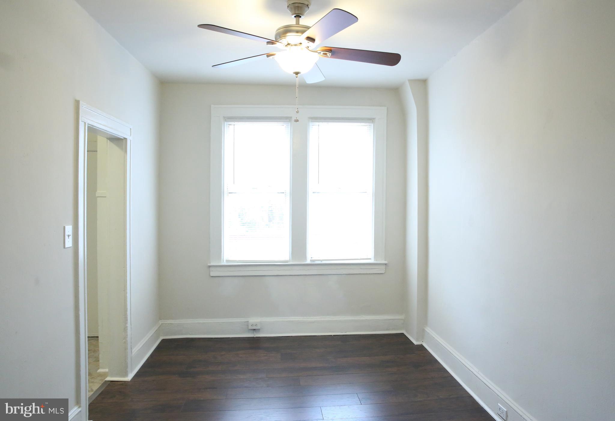 4852 Pimlico Road Baltimore, MD 21215 - Photo 8 of 40 an empty room with wooden floor fan and windows