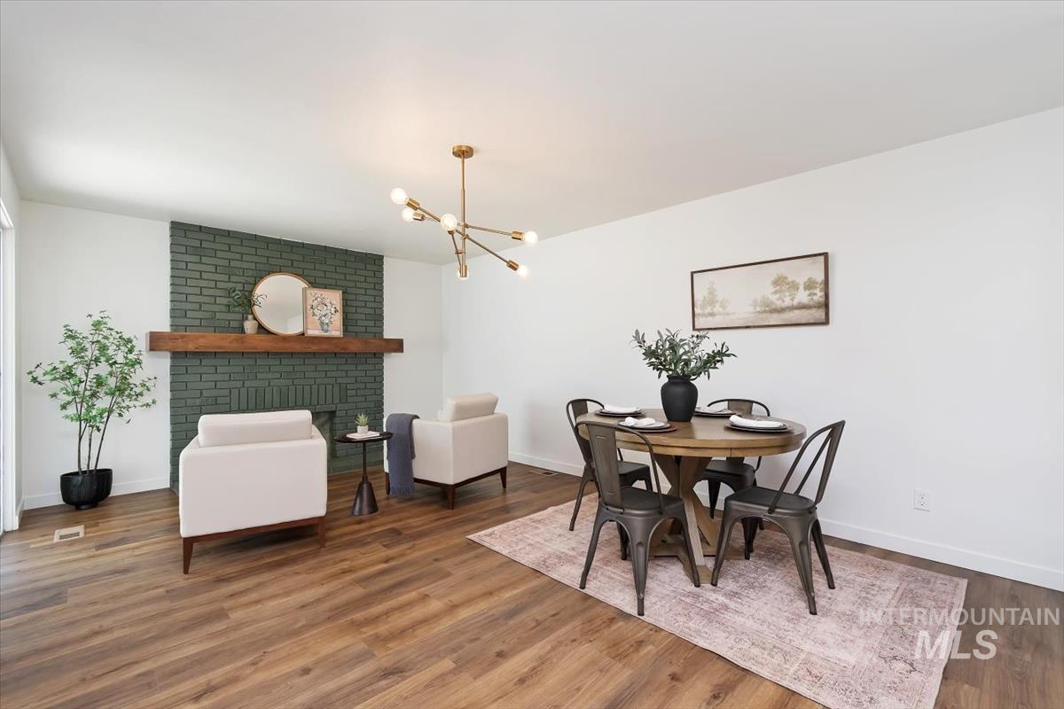 2217 North Middlefield Road Boise, ID 83704 - Photo 18 of 34 Open-concept living and dining area featuring wood-finish flooring, a painted brick fireplace with a wood mantel, a modern linear chandelier, and white wall finishes