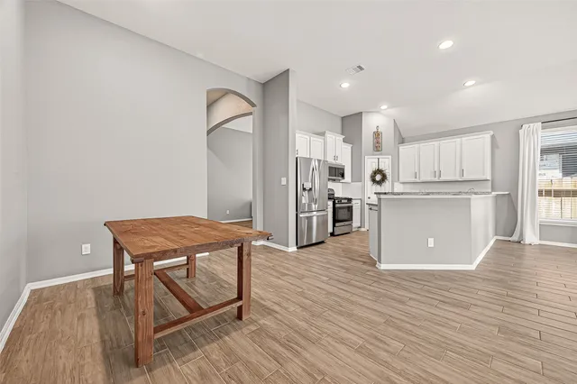 a room with stainless steel appliances wooden floor and a view of kitchen