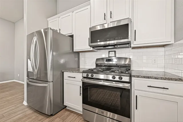 a kitchen with stainless steel appliances granite countertop a stove microwave and refrigerator