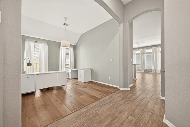 an empty room with wooden floor and windows