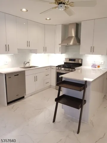 a kitchen with stainless steel appliances granite countertop a sink stove refrigerator and cabinets