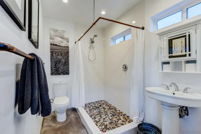 a bathroom with a sink a toilet a shower and a mirror