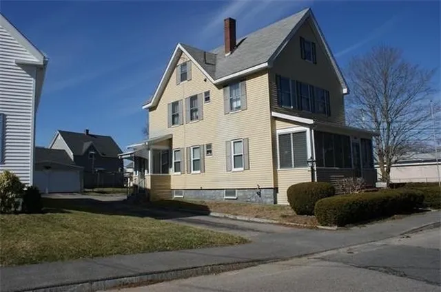 a view of a white house with large windows next to a yard