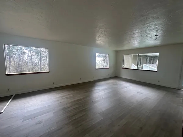 a view of an empty room with wooden floor and windows