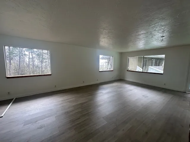a view of an empty room with wooden floor and windows
