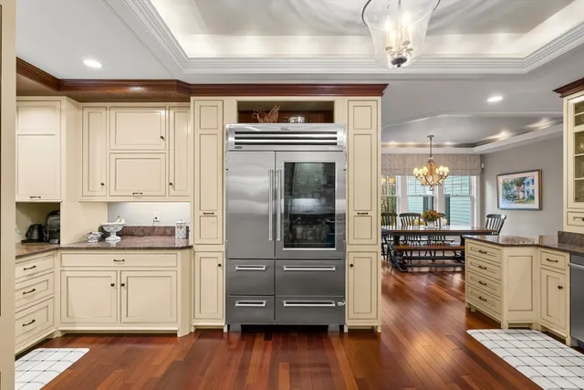 a kitchen with granite countertop a refrigerator oven a sink dishwasher and white cabinets with wooden floor