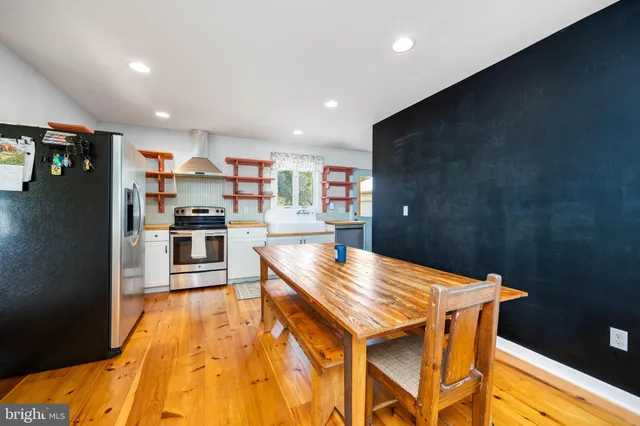 a kitchen with stainless steel appliances kitchen island granite countertop a table chairs in it and wooden floors