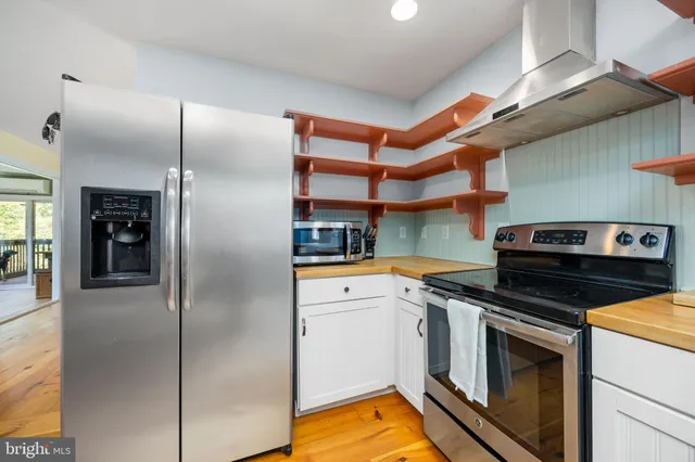 a kitchen with stainless steel appliances kitchen island granite countertop a table chairs in it and wooden floors