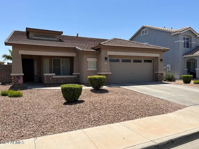 a view of a brick house with potted plants next to a road