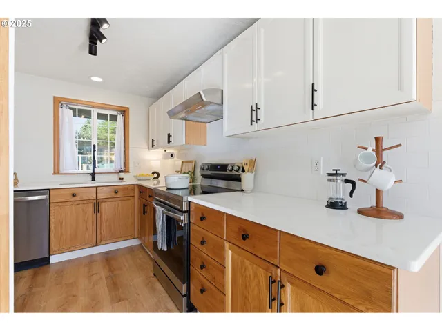 a kitchen with cabinets appliances a sink and a window