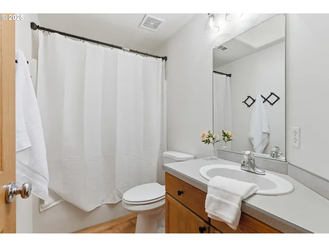 a bathroom with a sink a toilet a mirror and shower curtain