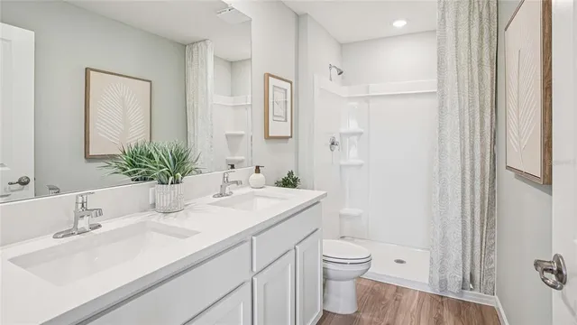 a bathroom with a sink toilet double vanity and shower