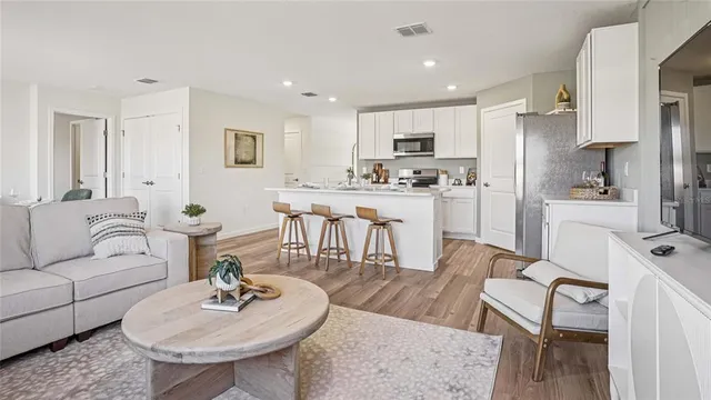 a living room with stainless steel appliances furniture a kitchen island a table and chairs