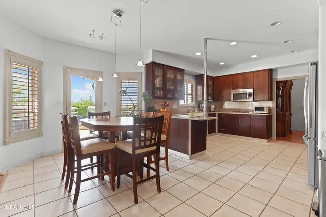 a kitchen with stainless steel appliances granite countertop a stove a sink a oven a dining table and chairs